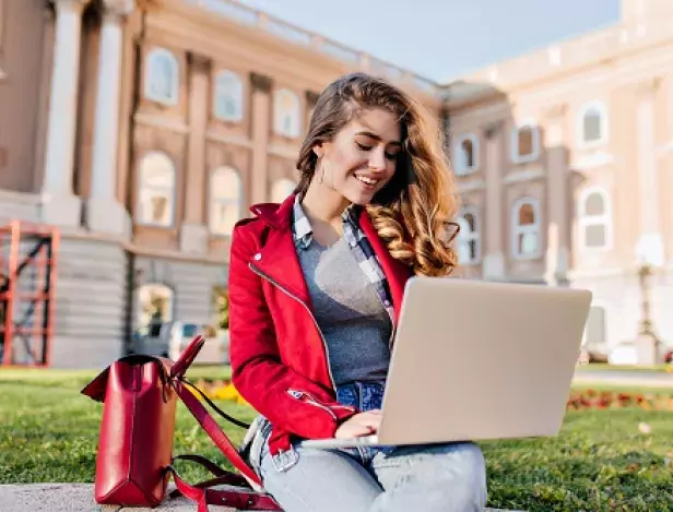 glamorous-female-student-red-jacket-sitting-yard-front-college-with-computer